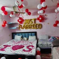 A simple and sweet 'Just Married' room decoration. The bed is covered in rose petals spelling 'I Love You', and the room is filled with red and white balloons to celebrate the new beginning.