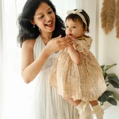 A mother's delight in her one-year-old daughter. Her expression of pure joy and the baby's curious gaze create a lively and heartwarming portrait.