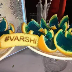 Fun and creative Jell-O shots served in orange wedges, accompanied by a biscuit branded with the couple's wedding hashtag, '#VARSHI'.
