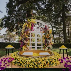 The central seating area for the Haldi, framed by a beautiful floral arch. The combination of yellow and purple created a stunning visual against the green landscape.