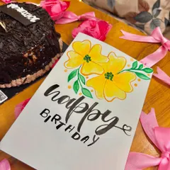 The birthday card pictured with a chocolate cake and pink ribbons.