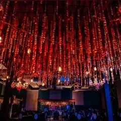 The ceiling of this sangeet hall was transformed with hanging red sequin strings and Edison bulbs. This created a dazzling, immersive effect over the entire space, setting the stage for a high-energy party.