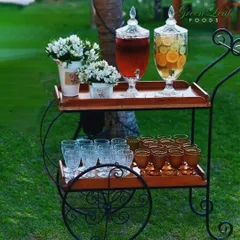 A charming drink cart set up for an outdoor wedding. This mobile station offers guests a choice of refreshing infused waters and juices, presented in an elegant and accessible way.