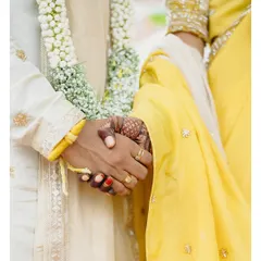 A close-up of the couple holding hands during their Maharashtrian wedding. This shot focuses on the details of the ritual, the bride's mehendi, and the symbolic joining of their lives.