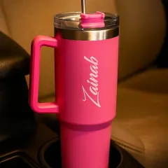 My large-capacity travel tumbler in hot pink, customized with the name "Zainab". The handle and straw-friendly lid make it perfect for taking on the go.