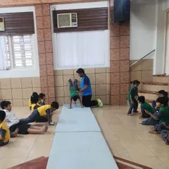 A coach carefully spots a young student during a gymnastics drill. Safety and proper technique are paramount as we introduce children to new physical challenges.