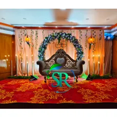 A full view of the elegant engagement backdrop with a floral arch and a classic carved sofa. The warm lighting creates a perfect romantic atmosphere.