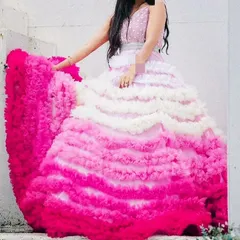 This unique ombre ruffled gown is a true work of art. The colors transition from white to shades of pink, creating a stunning visual effect that is perfect for a high-fashion photoshoot.