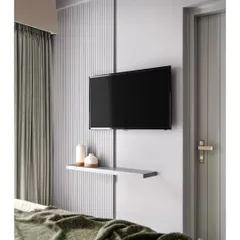 A minimalist TV unit solution for a bedroom. This design features a simple floating shelf and a vertical fluted panel that conceals wiring, maintaining a clean and uncluttered look.