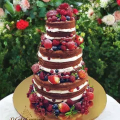 A celebration of fresh flavors. This multi-tiered "naked" cake is layered with fresh cream and generously decorated with a bounty of seasonal berries, including strawberries, blueberries, and raspberries.