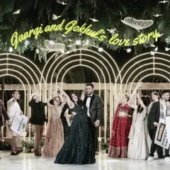The grand finale of a love story performance, with the couple and their friends celebrating under a neon sign with their names.