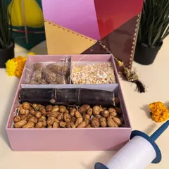 Our kite-themed Sankranti hamper box, opened to show the traditional treats inside: tilgul, Ellu Bella, sugarcane, and groundnuts.