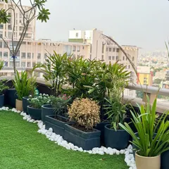 A simple yet elegant balcony setup. We used a row of modern planters with varied plants against a backdrop of artificial turf and white pebbles to create a clean and green urban garden with a city view.