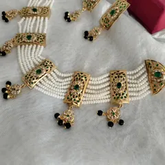 Here is a detailed shot of the Apsara necklace set in emerald green. This piece features multiple strands of pearls with intricately designed Jadau panels, finished with delicate bead drops.