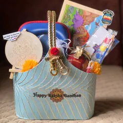 An elegant Raksha Bandhan hamper in a beautiful blue and gold basket. I've included a paintable craft, a puzzle, and other gifts suitable for both a brother and his family.
