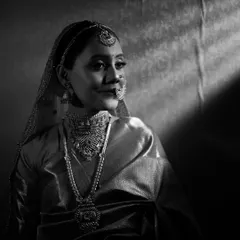 A soft, elegant black and white portrait of the bride. The gentle light creates a serene and timeless feel, highlighting her delicate features and jewelry.