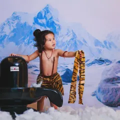 A powerful portrait of a little boy dressed as Mahadev, set against a backdrop of the snowy Himalayas.