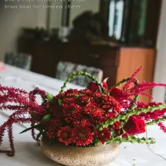 For a more traditional and rich aesthetic, this centerpiece uses a lush arrangement of deep red chrysanthemums and amaranthus in an antique brass bowl. This design adds timeless charm to a VIP dining table.