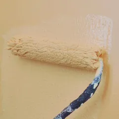 A close-up of a paint roller applying a thick, even coat of paint. Using the right tools is essential for achieving a professional, textured, or smooth finish.