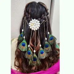 A captivating hairstyle featuring a custom accessory made with shells and peacock feathers. This is a perfect example of how we can create a unique, statement piece for your hair.