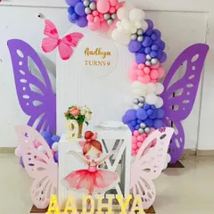 A beautiful butterfly and ballerina theme for a 9th birthday. The design uses large, intricate butterfly wing cutouts to frame an arched backdrop, complemented by a pink, purple, and white balloon garland.