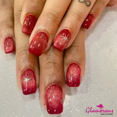 A dramatic and glamorous look, these nails feature a deep red cat-eye effect with a sparkling starburst on the accent nails.