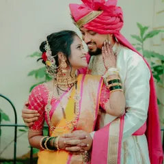 A tender embrace between a bride and groom in their stunning Maharashtrian wedding attire. The bride's yellow and pink saree complements the groom's traditional outfit perfectly.