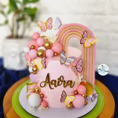 A dreamy butterfly and rainbow cake for a little one's birthday. The pastel pinks, gold details, and cascade of spheres make this a whimsical and magical celebration cake.