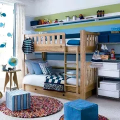 A classic wooden bunk bed is the centerpiece of this charming kids' room, designed with a subtle nautical theme. We used shades of blue and white, along with practical storage boxes, to create a space that is both tidy and full of character.
