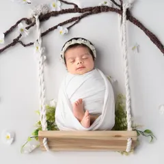 A baby sleeping peacefully on a swing under a cherry blossom branch. This setup creates such a dreamy and artistic feel for a newborn photoshoot.