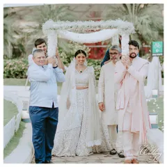 A beautiful bride making her "Din Shagna Da" entrance under a delicate floral canopy held by her brothers and father.