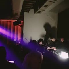 A wider view of the DJ booth, with purple spotlights cutting through the dark. This shot captures the intimate and moody atmosphere of a lounge set.