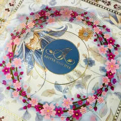 A close-up of the lid, showcasing the three-dimensional quality of the floral wreath made from decorative gems. The couple's monogram sits in the center, creating a beautiful and personal focal point for this luxury invitation.