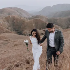 A candid moment of the couple walking hand-in-hand through a field of golden grass, capturing the feeling of a shared journey in a beautiful, natural setting.