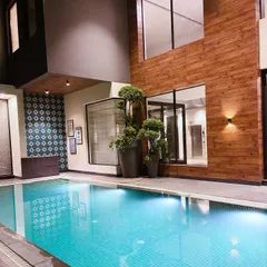 A different view of the pool at night, showing how the lighting highlights the topiary plants and the texture of the wood-paneled wall.