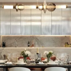 The Luna series provides elegant illumination over a formal dining table. The combination of illuminated tubes and decorative glass elements adds a layer of glamour and sophistication.