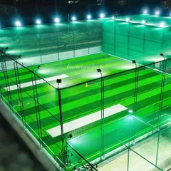 Another view of a lighted sports arena at night. The artificial turf reflects light evenly, ensuring great visibility for evening cricket or football matches.