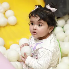 A curious toddler explores the textures and shapes of the balls in our clean and safe ball pit.