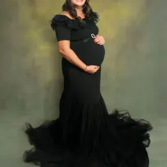Our black off-the-shoulder mermaid gown is a client favorite. It offers a timeless, elegant look that beautifully accentuates the baby bump, perfect for both studio and outdoor settings.