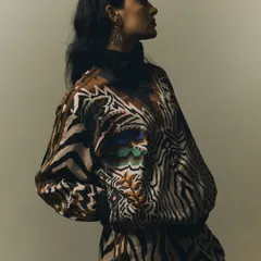 A profile shot that uses shadow and light to sculpt the model's form and highlight the texture of the printed fabric. The mood is quiet and contemplative, adding depth to the fashion story.