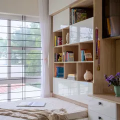 The reading nook next to the window is a perfect spot for a child to curl up with a book. The built-in bookshelf is designed for easy access, encouraging a love for reading.