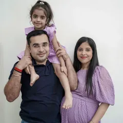 A lovely family portrait taken during an in-home maternity shoot. The older sister sits on her father's shoulders while her mother shows her baby bump.