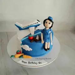 A birthday cake customized for a cabin crew member at Indigo Airlines. The design includes a plane, a handcrafted figurine in uniform, and healthy vegetables.