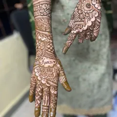 Hiding the groom's name is a fun tradition. In this design, the name 'Khalil' is written in a heart shape on the palm, surrounded by intricate patterns.