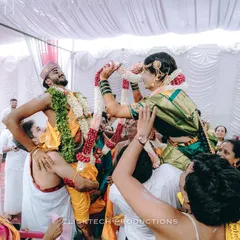 The fun and games of a South Indian wedding. This candid shot captures the bride and groom being playfully lifted on their relatives' shoulders during the garland exchange ceremony.