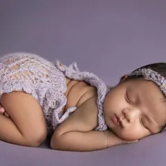 A closer shot of the baby girl in the lavender setup, highlighting her peaceful expression and tiny, perfect features.