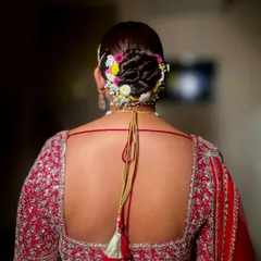 A classic bridal bun with a beautiful woven texture, adorned with a mix of colorful flowers and baby's breath. This look is perfect for a traditional wedding ceremony.