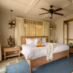 A wider view of the bedroom, showcasing the coffered ceiling and the use of natural materials like wood and stone. The color palette is intentionally muted to keep the focus on the incredible views outside.