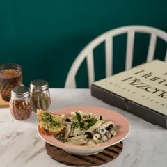 A creamy bowl of pasta from The Humble Pizzeria. The soft lighting and simple plating create an inviting and comforting image, perfect for showcasing a classic cafe dish.