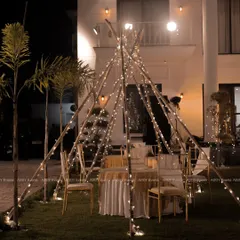Another look at the fairy-lit teepee dining setup, this time with a grand villa in the background, showing how we can transform any space into a magical setting.